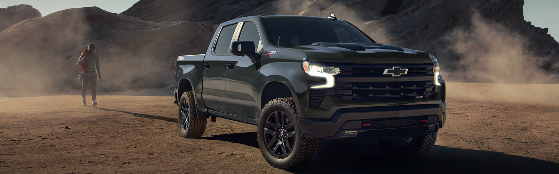 2026 Chevrolet Silverado parked in a desert landscape with a person walking nearby.
