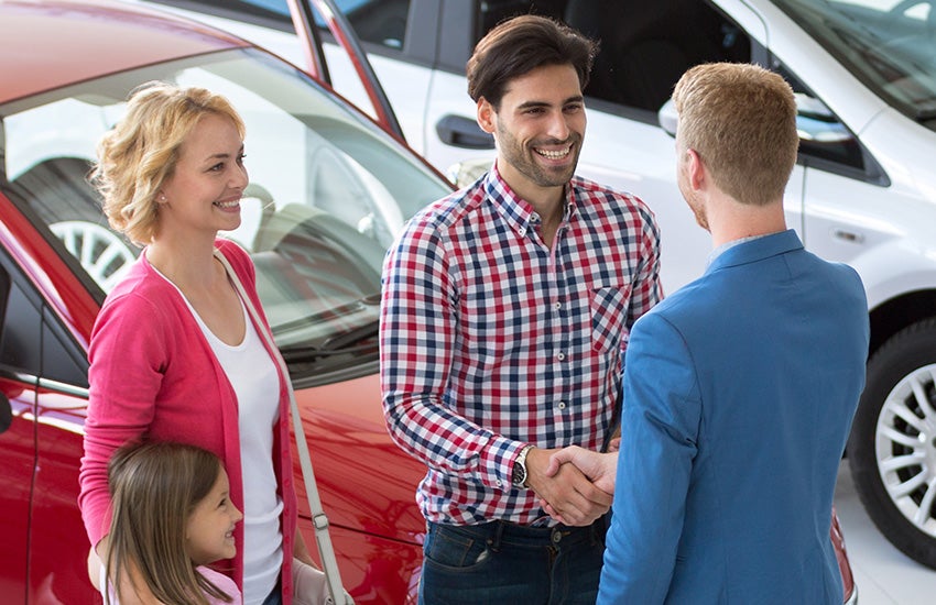Family meeting with dealership staff next to new car